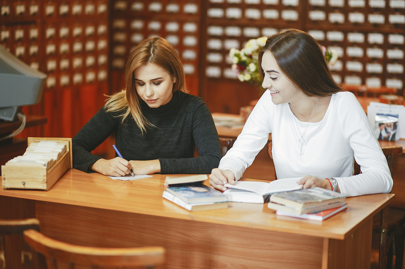 two women sitting at a table with books